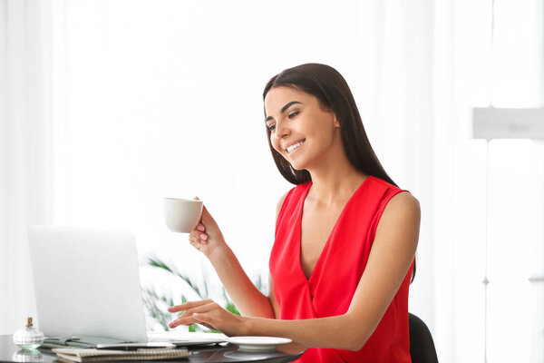 Female blogger with laptop drinking coffee in cafe