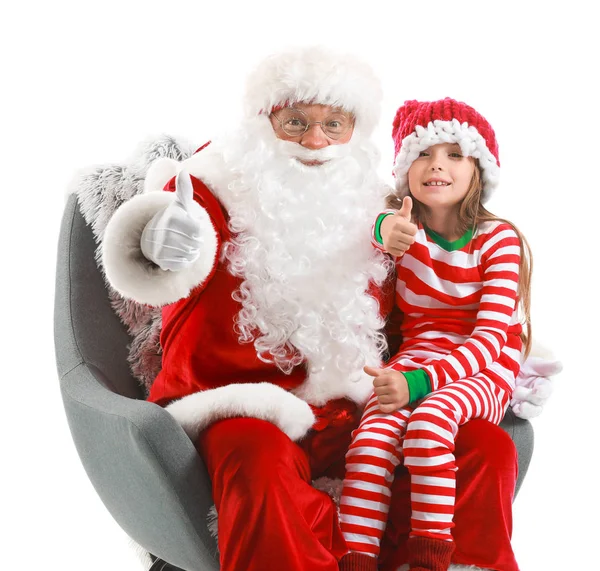 Jultomten och liten flicka som visar tummen upp när du sitter i fåtölj mot vit bakgrund — Stockfoto