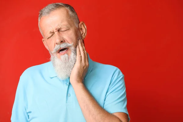 Homme âgé souffrant de maux de dents sur fond de couleur — Photo