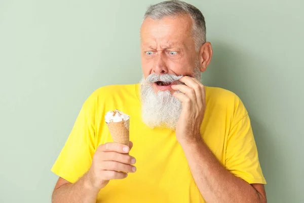 Hombre mayor con dientes sensibles y helado frío sobre fondo de color —  Fotos de Stock