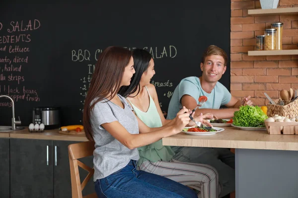 Happy friends eating together in kitchen — Stock Photo, Image