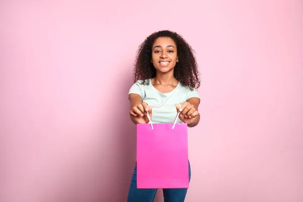 Porträt der schönen afrikanisch-amerikanischen Frau mit Einkaufstasche auf farbigem Hintergrund — Stockfoto