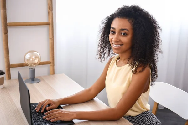 Portrait of beautiful African-American businesswoman working on laptop in office — Stock Photo, Image