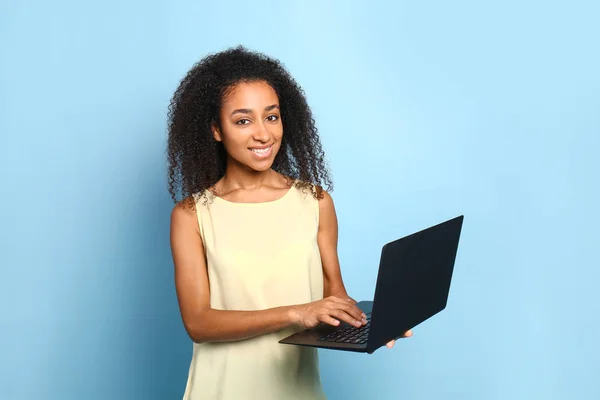 Portrait of beautiful African-American woman with laptop on color background — Stock Photo, Image