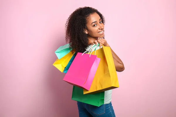 Portrét nádherné afroamerické ženy s nákupními taškami na barevném pozadí — Stock fotografie