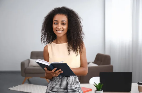Portrait of beautiful African-American businesswoman with notebook in office — Stock Photo, Image