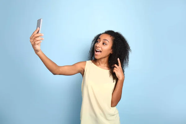 Retrato de mulher afro-americana feliz tomando selfie em fundo de cor — Fotografia de Stock