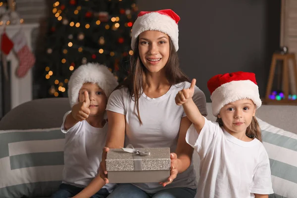 Mulher e seus filhinhos com presente em casa na véspera de Natal — Fotografia de Stock