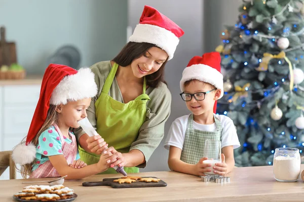 Woman and her little children preparing Christmas cookies at home — Stock Photo, Image
