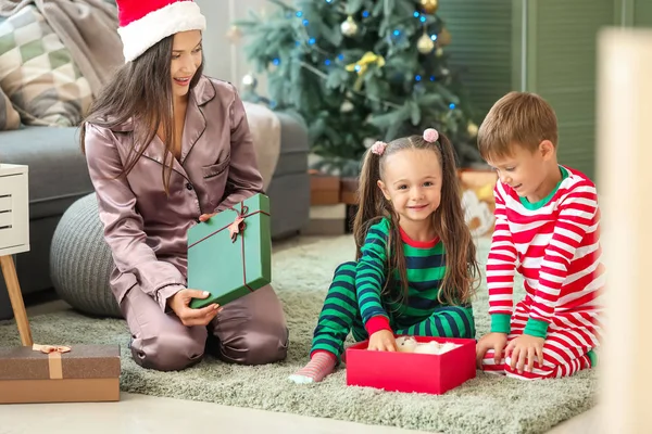 Mulher e seus filhinhos com presentes de Natal em casa — Fotografia de Stock