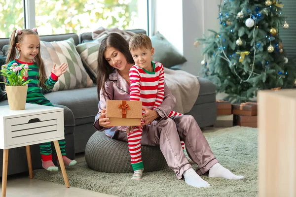 Frau und ihre kleinen Kinder mit Weihnachtsgeschenk zu Hause — Stockfoto