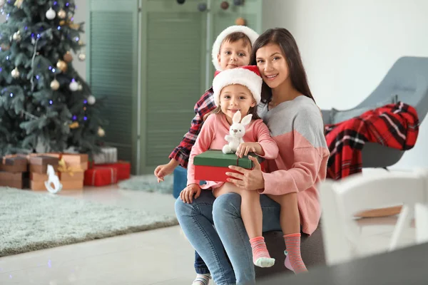 クリスマスイブに家で贈り物を持つ女性と彼女の小さな子供たち — ストック写真