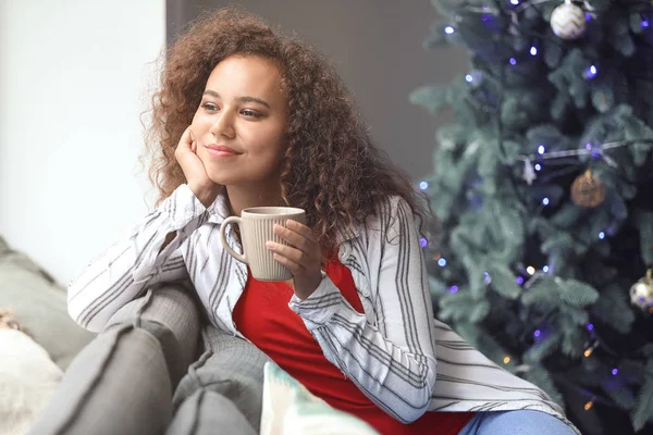 Young African-American woman drinking hot chocolate at home on Christmas eve — Stock Photo, Image