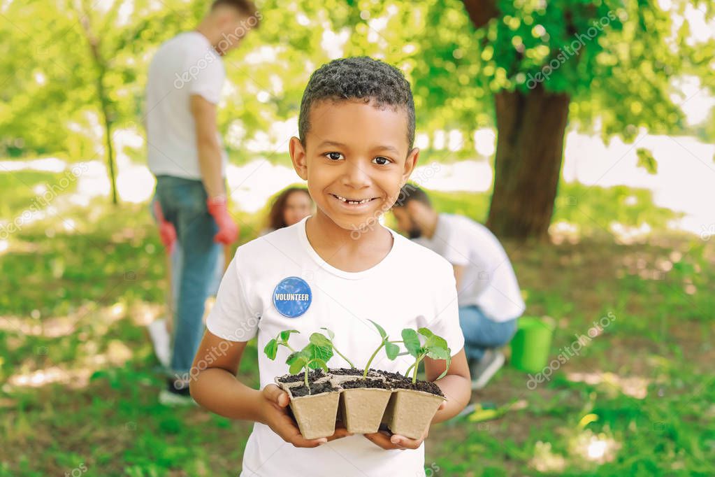 Little African-American volunteer with young plants outdoors