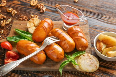 Tahta masada lezzetli ızgara sosis, sos ve patates ile Kurulu