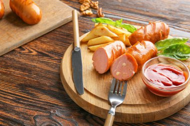 Tahta masada lezzetli ızgara sosis, sos ve patates ile Kurulu