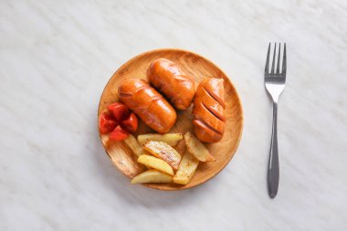 Hafif arka planda lezzetli ızgara sosis ve patates ile Plaka