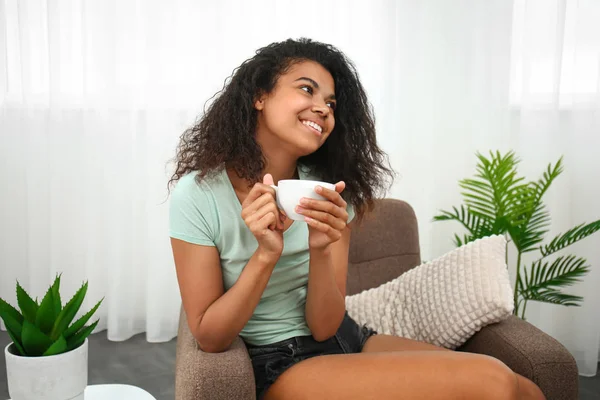 Beautiful young African-American woman drinking coffee at home — Stock Photo, Image