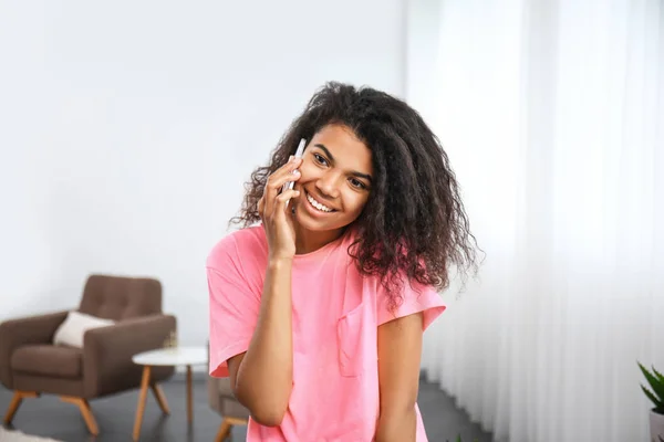 Young African-American woman talking by phone at home — Stock Photo, Image