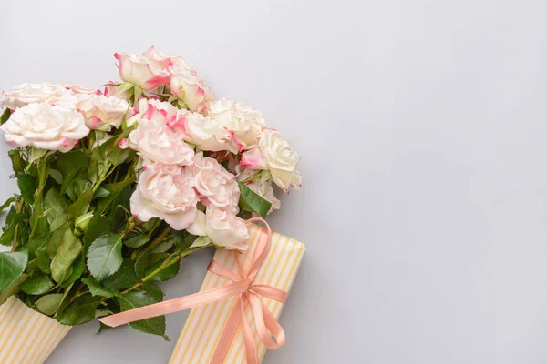 Gift box and beautiful flowers on light background — Stock Photo, Image