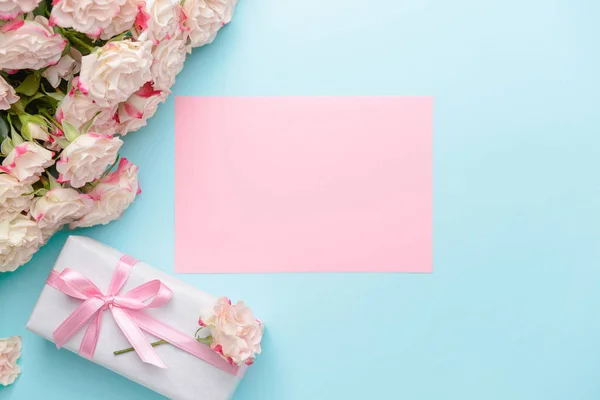Подарочная коробка, открытка и красивые цветы на цветном фоне — стоковое фото