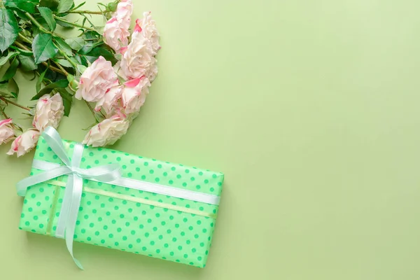 Gift box and beautiful flowers on color background — Stock Photo, Image