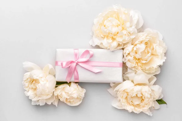 Gift box and beautiful flowers on light background — Stock Photo, Image