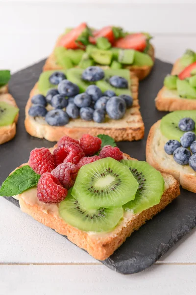 Tasty sandwiches with kiwi and berries on slate plate, closeup — Stock Photo, Image