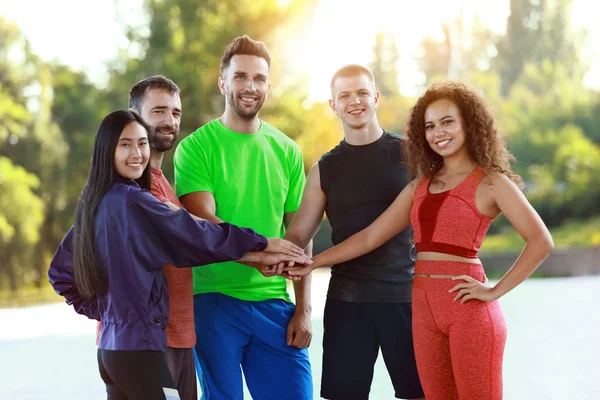 Group of young sporty people putting hands together outdoors — Stock Photo, Image