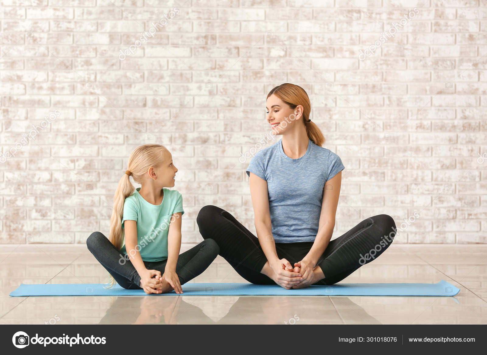 Mother with little girl doing yoga indoors Stock Photo by