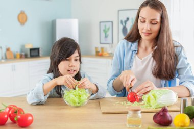 Sevimli kızı ile anne mutfakta sebze salatası hazırlanıyor
