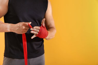 Renkli arka plana karşı bilek bantları uygulayarak sportif genç adam