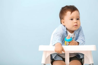 Renkli arka plan karşı yüksek sandalyede oturan Nibbler ile sevimli küçük çocuk