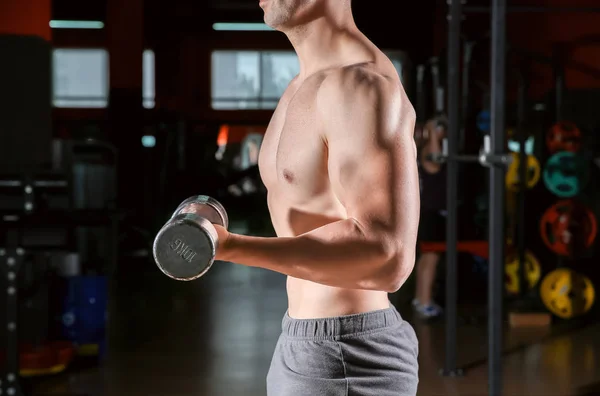 Sporty young man with dumbbells in gym — Stock Photo, Image