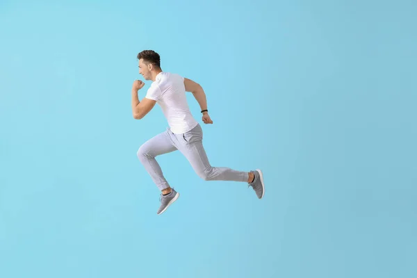 Running young man on color background — Stock Photo, Image