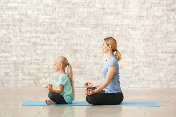 Madre con niña haciendo yoga en el interior — Foto de Stock