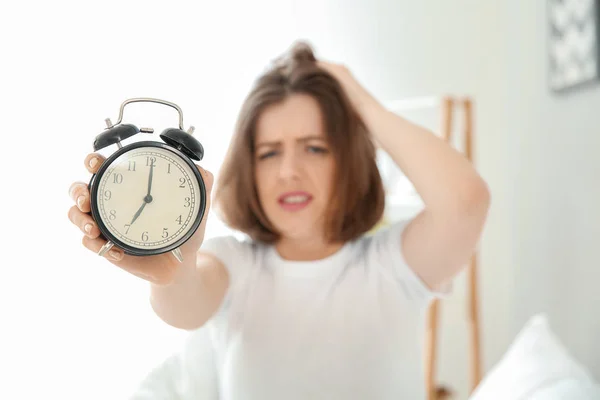 Morning of displeased sleepy young woman with alarm clock in bedroom — Stock Photo, Image
