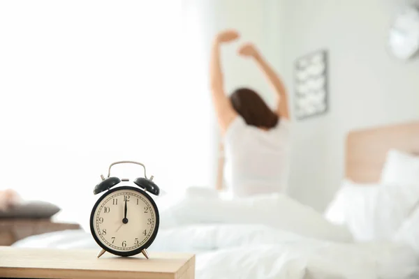 Alarm clock on table in bedroom of young woman — Stock Photo, Image