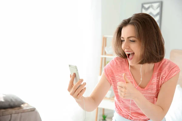 Beautiful young woman having fun while listening to music in bedroom — Stock Photo, Image
