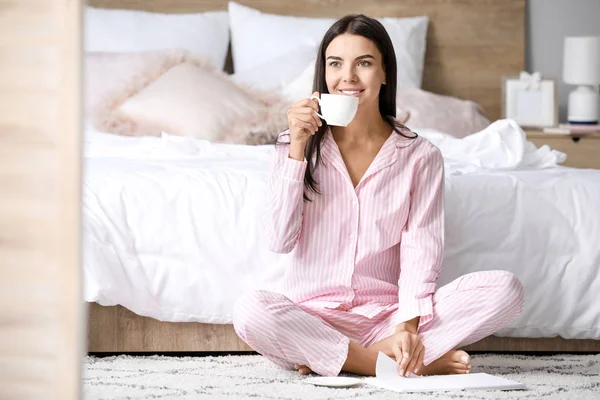 Morgen der schönen jungen Frau, die Kaffee trinkt, während sie Buch im Schlafzimmer liest — Stockfoto