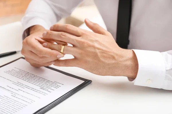 Man taking wedding ring off his finger at lawyer\'s office. Concept of divorce