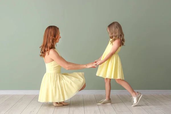 Beautiful woman and her little daughter near color wall — Stock Photo, Image