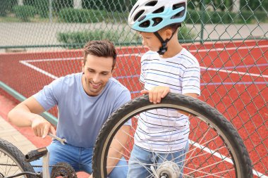 Baba ve oğlu açık havada bisiklet tamir