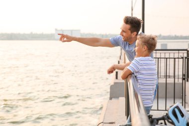 Baba ve küçük oğlu nehir kenarında bisikletle