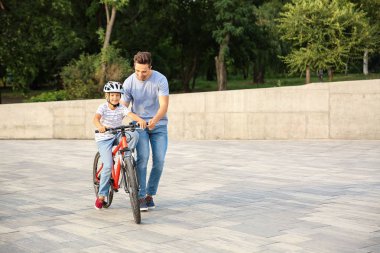Baba oğluna dışarıda bisiklete binmeyi öğretiyor.