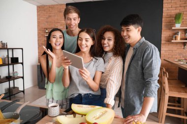 Mutfakta birlikte yemek yaparken tablet bilgisayar arama tarifi ile mutlu arkadaşlar