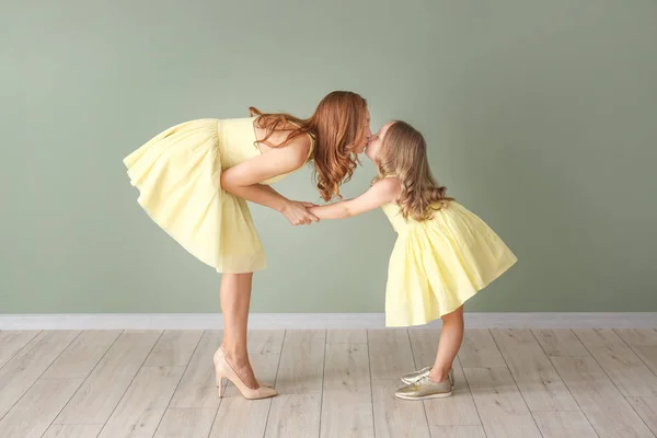 Beautiful woman and her little daughter near color wall — Stock Photo, Image