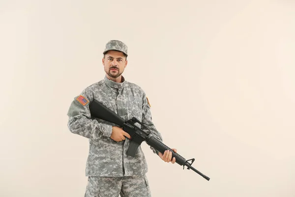 Soldier with assault rifle on light background — Stock Photo, Image