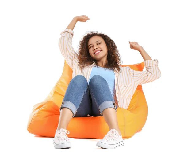 Beautiful African-American woman relaxing on beanbag against white background — Stock Photo, Image