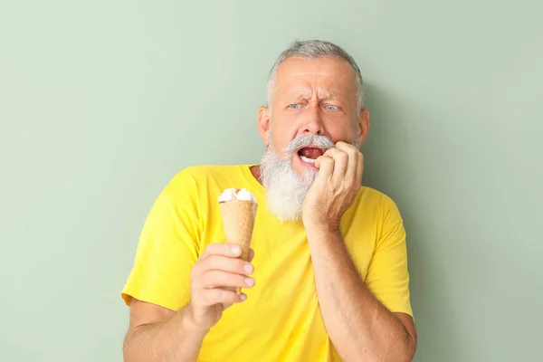 Senior man met gevoelige tanden en koud ijs op kleur achtergrond — Stockfoto